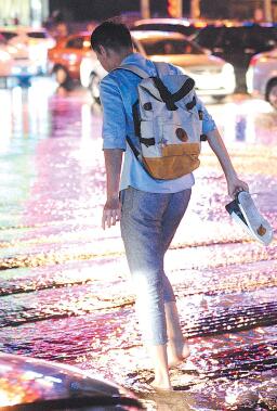 6日21点左右， 济南遭遇急雨大风， 一时间街道变成了河流， 行人措手不及， 提鞋蹚水回家， 很多人成了落汤鸡。 本报记者 周青先 摄